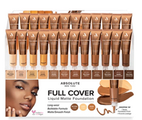 Thumbnail for A retail display box filled with tubes of Absolute New York Full Cover Liquid Matte Foundation in various warm skin-tone shades, with shade labels below each tube and a model's face shown in the lower left.