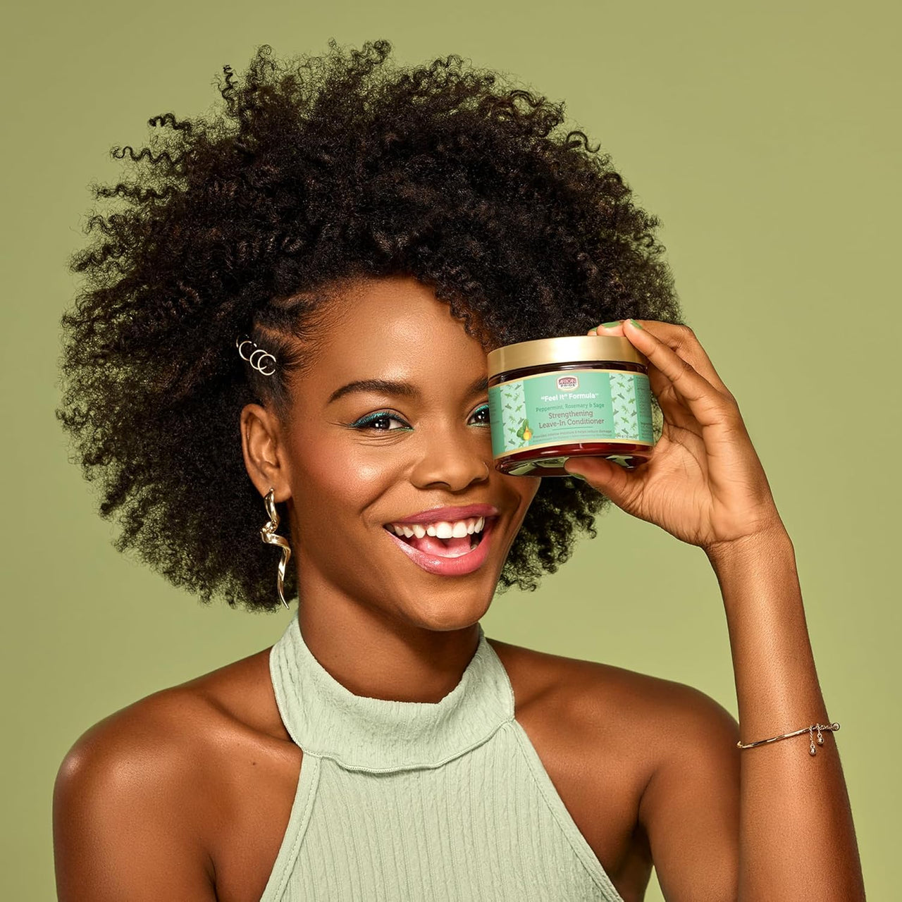 Woman holding a jar of hair care product against a green background
