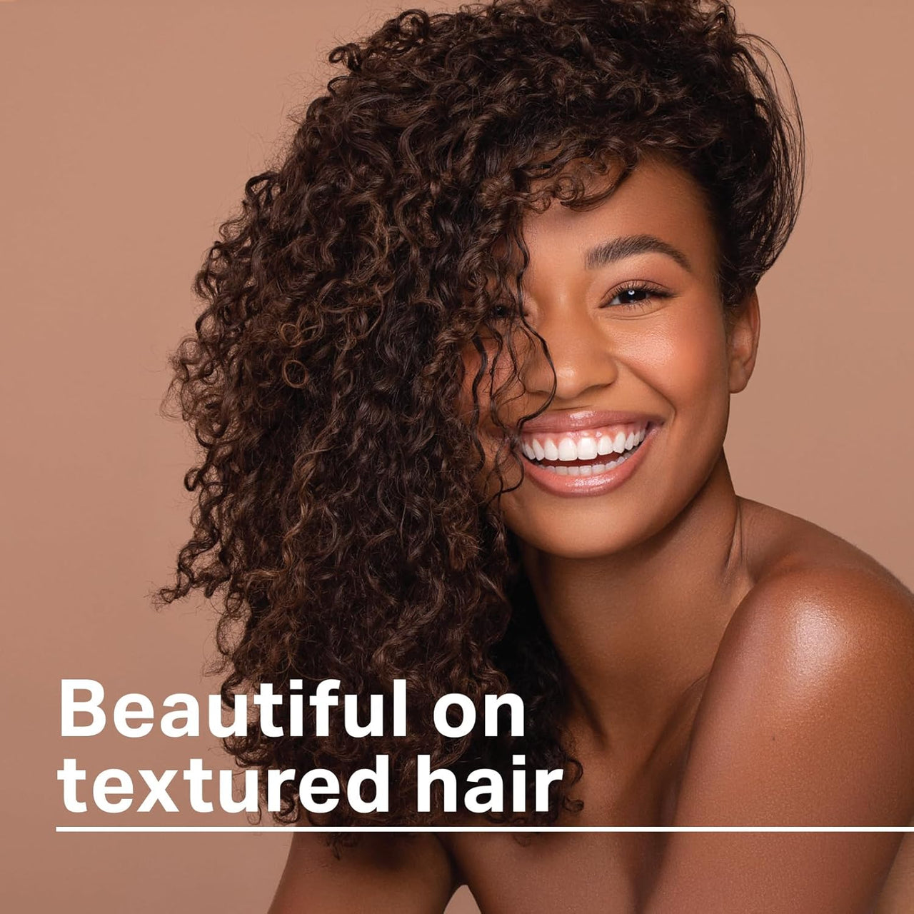 Woman with curly hair smiling against a brown background with text 'Beautiful on textured hair'.
