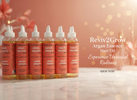 Thumbnail for Multiple bottles of Reviv2Grow Argan Essence Hair Oil on a shelf.