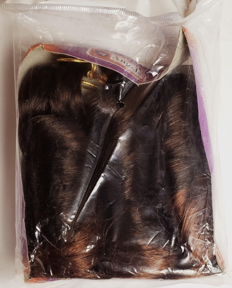 Packaged hair extensions in clear plastic with a purple label.