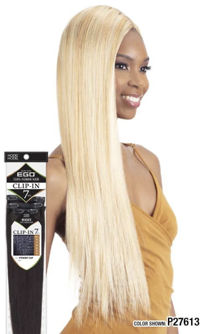 A woman modeling a long, straight, platinum blonde clip-in hair extension next to its retail packaging. The packaging is black and white with the brand name 'EGO' and product name 'Clip-In 7'.