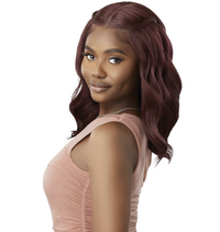 Thumbnail for A woman with shoulder-length, wavy burgundy hair wearing a light pink sleeveless top, shown from a side-back angle against a plain white background.