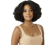 Thumbnail for A woman with a short, curly black wig wearing a beige scoop-neck top, shown against a plain white background.
