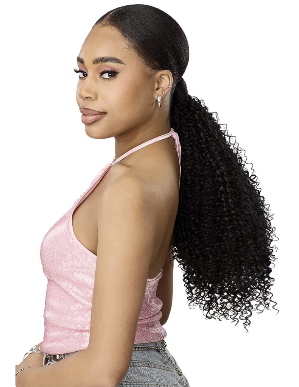 A woman with long, dark, curly hair in a low ponytail, wearing a sparkling light pink halter top and denim jeans, shown from a side-back profile against a solid white background.