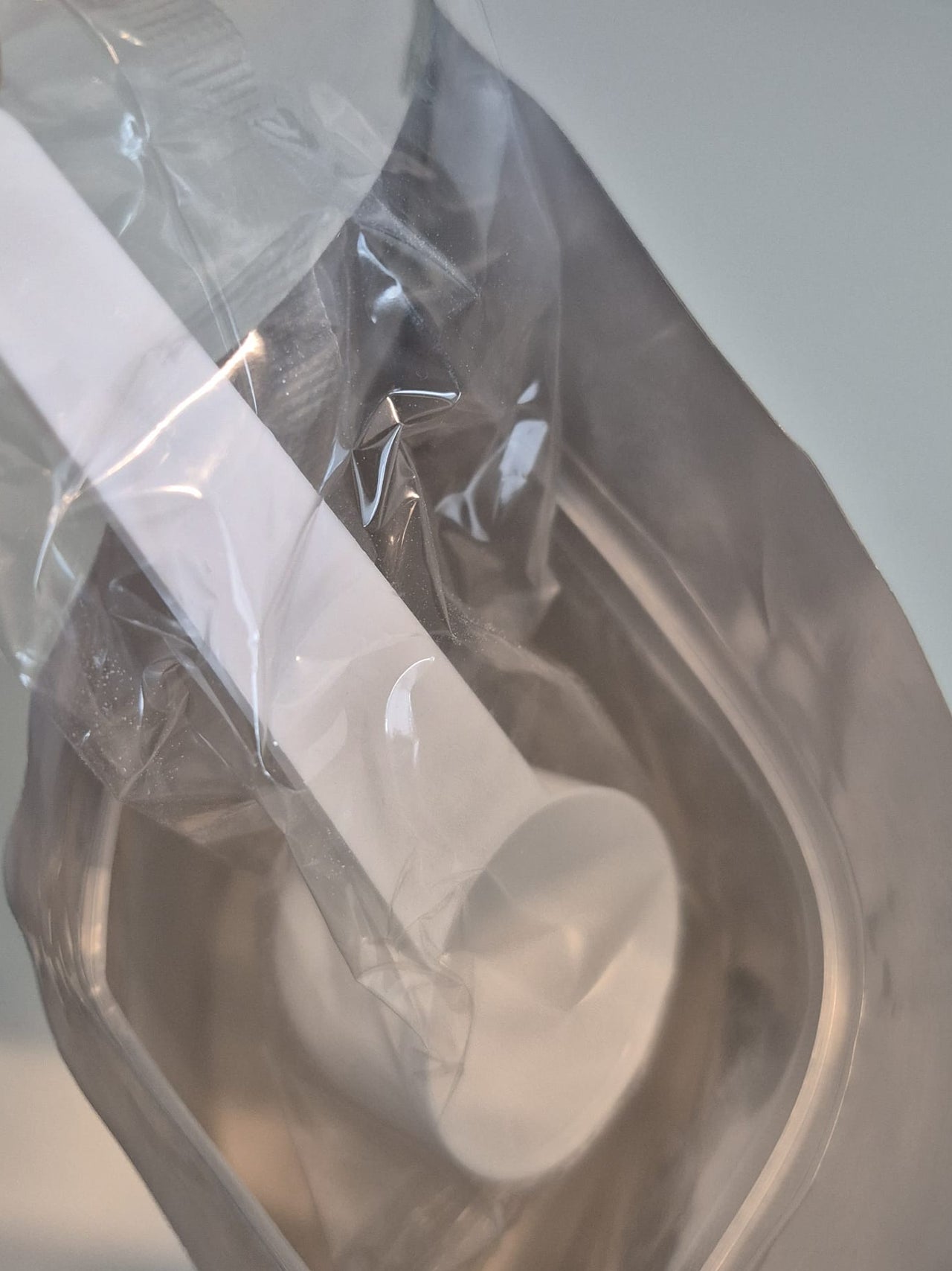White earbud in a clear plastic bag on a white background