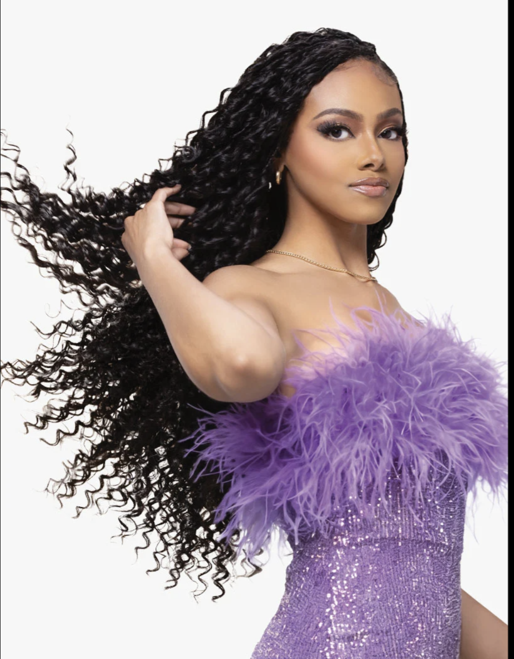 A woman with long, voluminous, tightly curled black hair is shown against a plain white background, wearing a strapless lavender sequined dress with a fluffy feathered neckline.