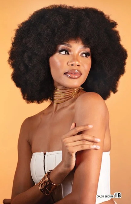 Woman with voluminous afro hair wearing a white strapless dress against an orange background